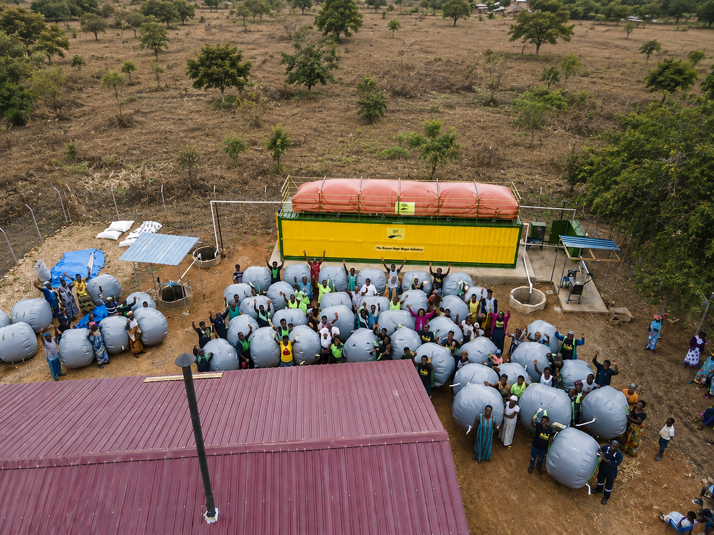 Aerial view of a community gathered with their biogas distribution pods beside the container digester