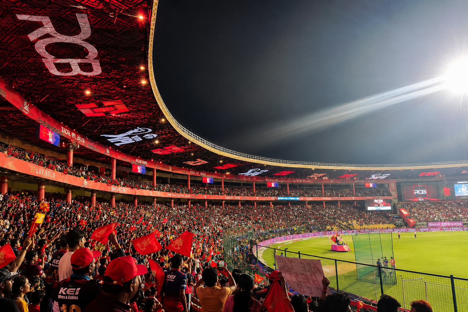 A packed cricket stadium during an RCB home match, with the illuminated field and spectators visible across the stands.