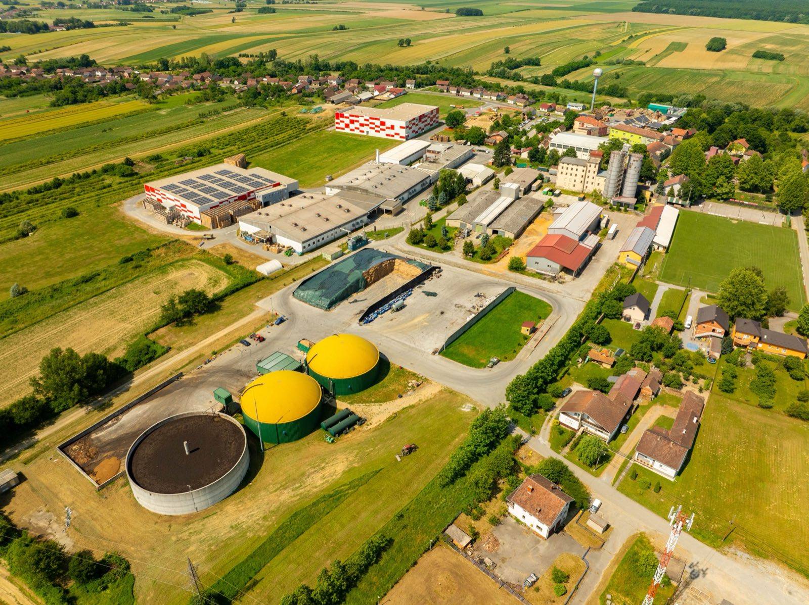 An aerial view of a biogas plant with dome digesters amid farmland